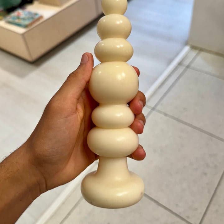 Hand-held phone photo of a knubby white candle in a shop