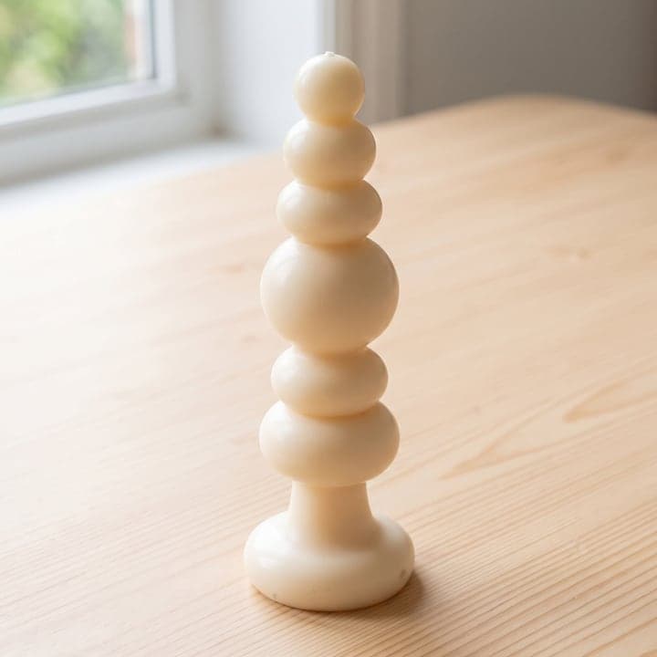 The same candle rendered on a wooden table by a window