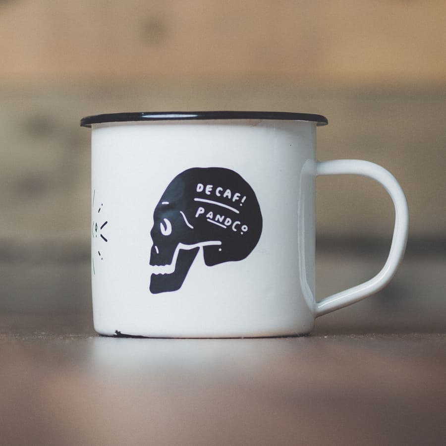 Seller's phone photo of an enamel mug on a wooden table